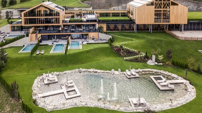 L’esclusività in foto: il nostro chalet in Alto Adige di lusso Area benessere moderna con piscine esterne e laghetto in paesaggio verde