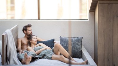 Coppia rilassata insieme su un letto in legno con cuscini e coperte