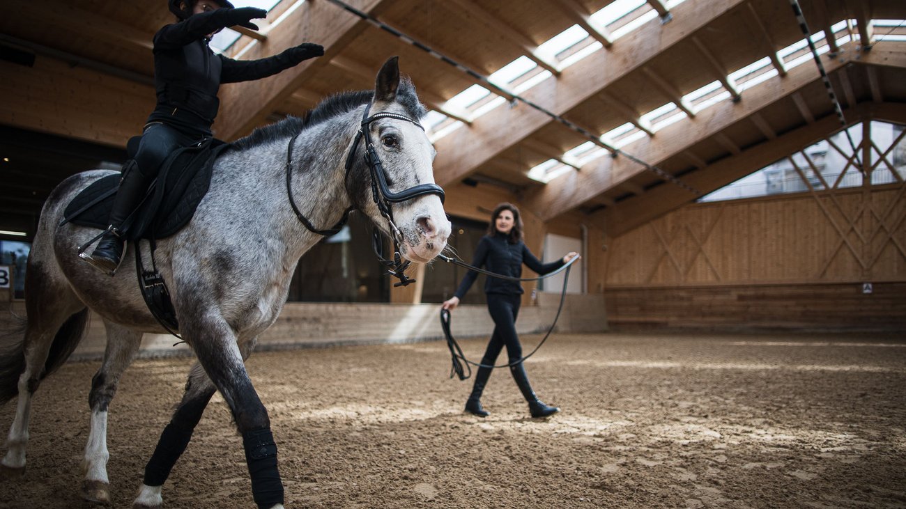 Allenamento di equitazione in maneggio con cavaliere a cavallo e istruttrice