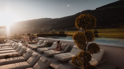 Sunset over a pool terrace with loungers and mountains in the background