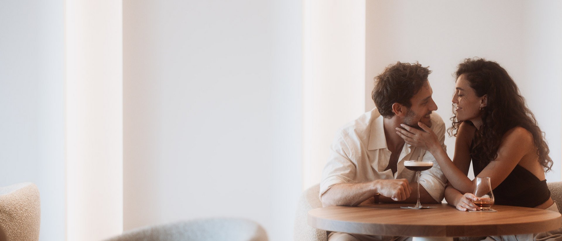 Couple sharing an intimate moment over drinks at a cozy bar table