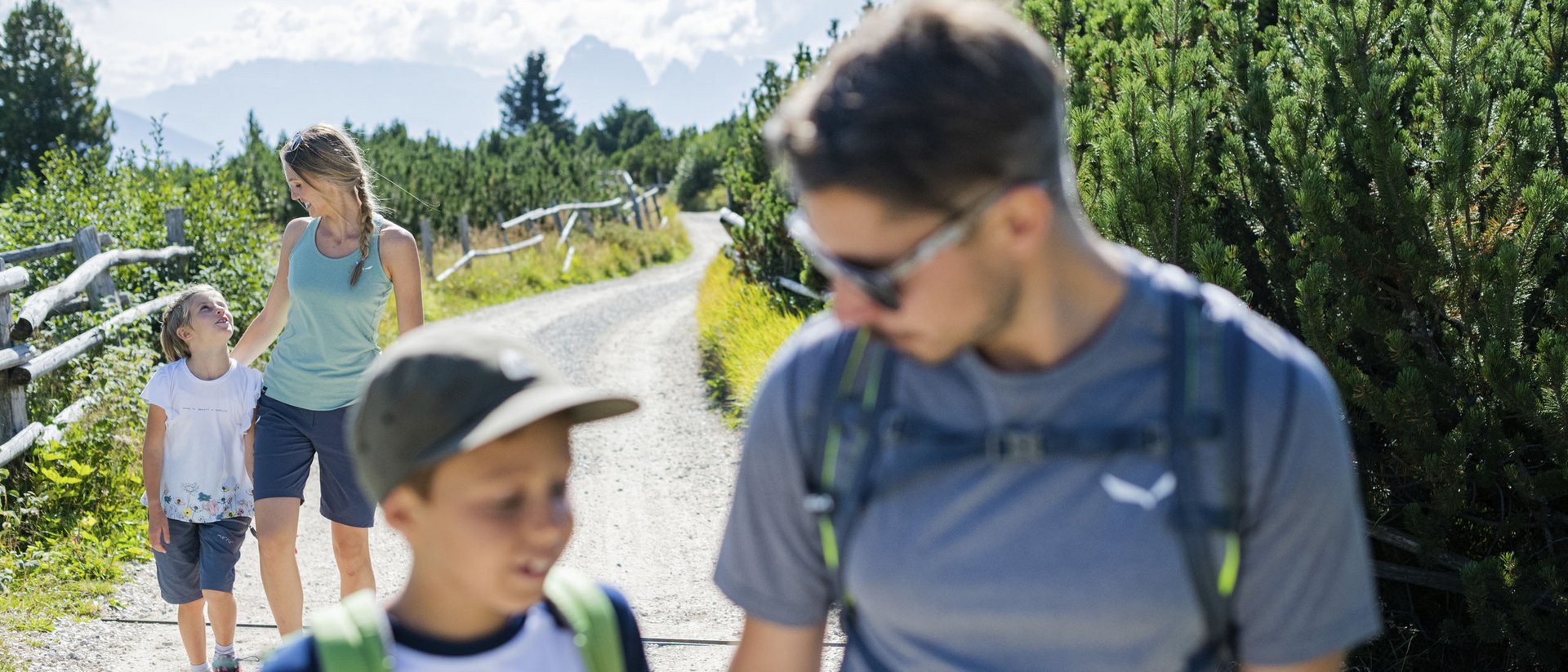 Sentiero delle fiabe a Tesido, attrazione per tutti Famiglia che cammina su un sentiero di montagna soleggiato