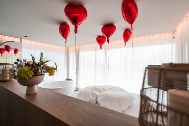 Romantisches Schlafzimmer mit roten Herzluftballons an der Decke