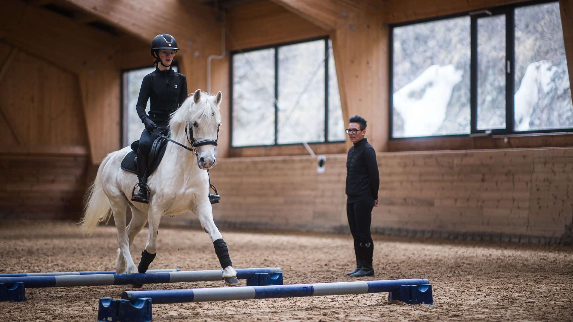 Lezione di equitazione in una scuderia con cavallo, amazzone e istruttrice
