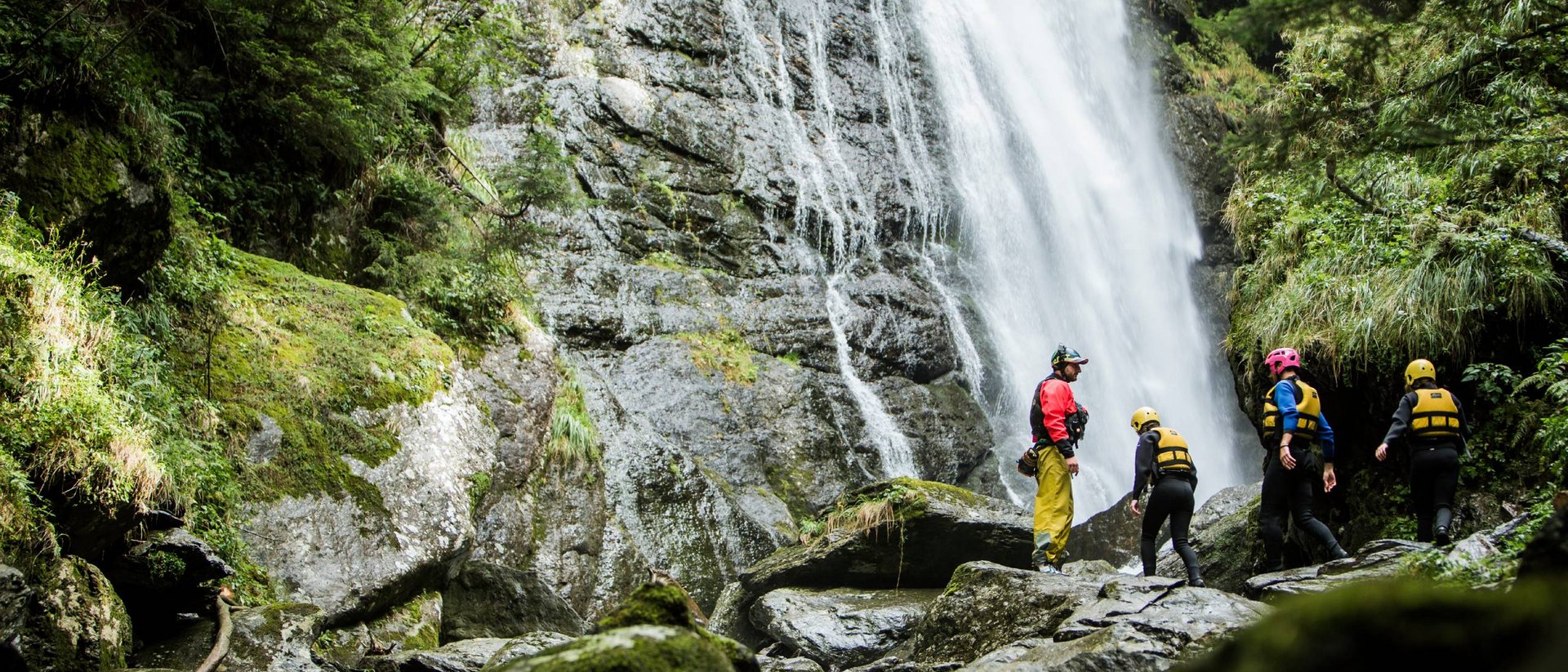 Canyoning, Rafting und Paragliding im Sommer Gruppo di persone con equipaggiamento di sicurezza davanti a una cascata rocciosa