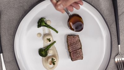 L’esclusività in foto: il nostro chalet in Alto Adige di lusso Impiattamento di un piatto raffinato con bistecca, salsa e verdure su piatto bianco