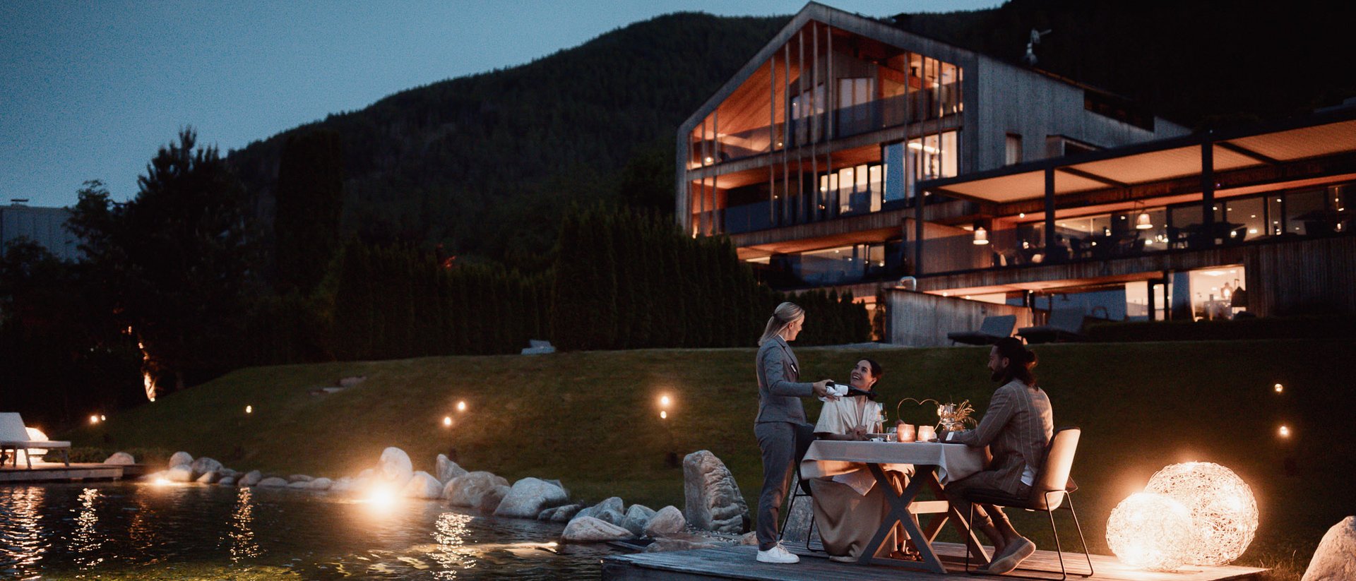 Dinner by the lake in front of modern house in the mountains at dusk