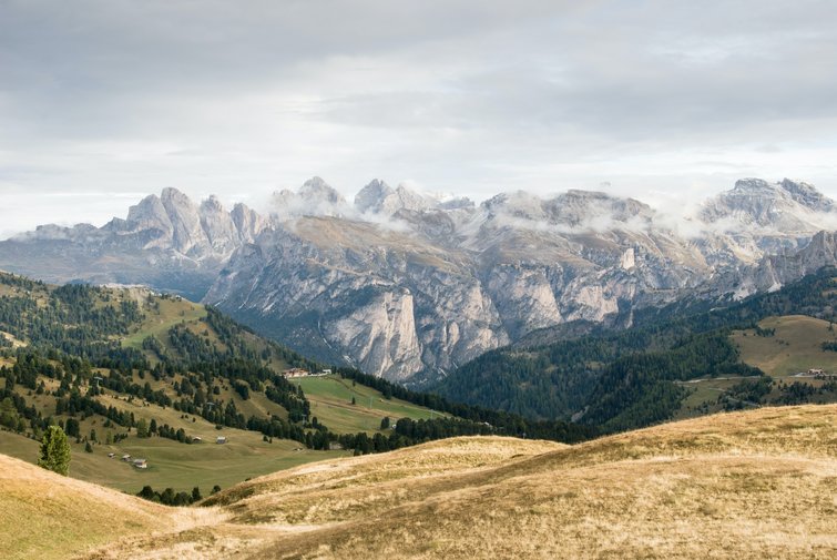 Autumn alpine landscape with mountains and green valleys under cloudy sky