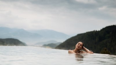 L’esclusività in foto: il nostro chalet in Alto Adige di lusso Donna rilassata in piscina a sfioro con vista sulle montagne e cielo nuvoloso