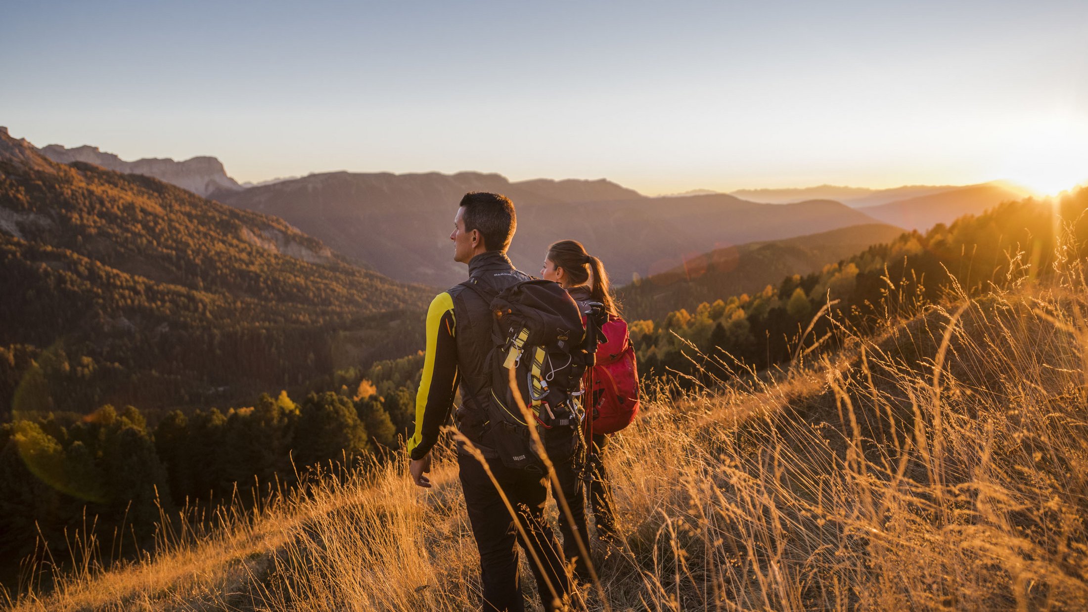 Due escursionisti ammirano il tramonto sulle montagne