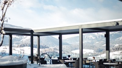 Terrazza innevata con tavoli, sedie e vista sulle montagne in inverno