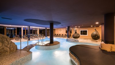 The best photos from our hotel in South Tyrol that kids love Modern indoor pool with lounge chairs and decorative hanging seats