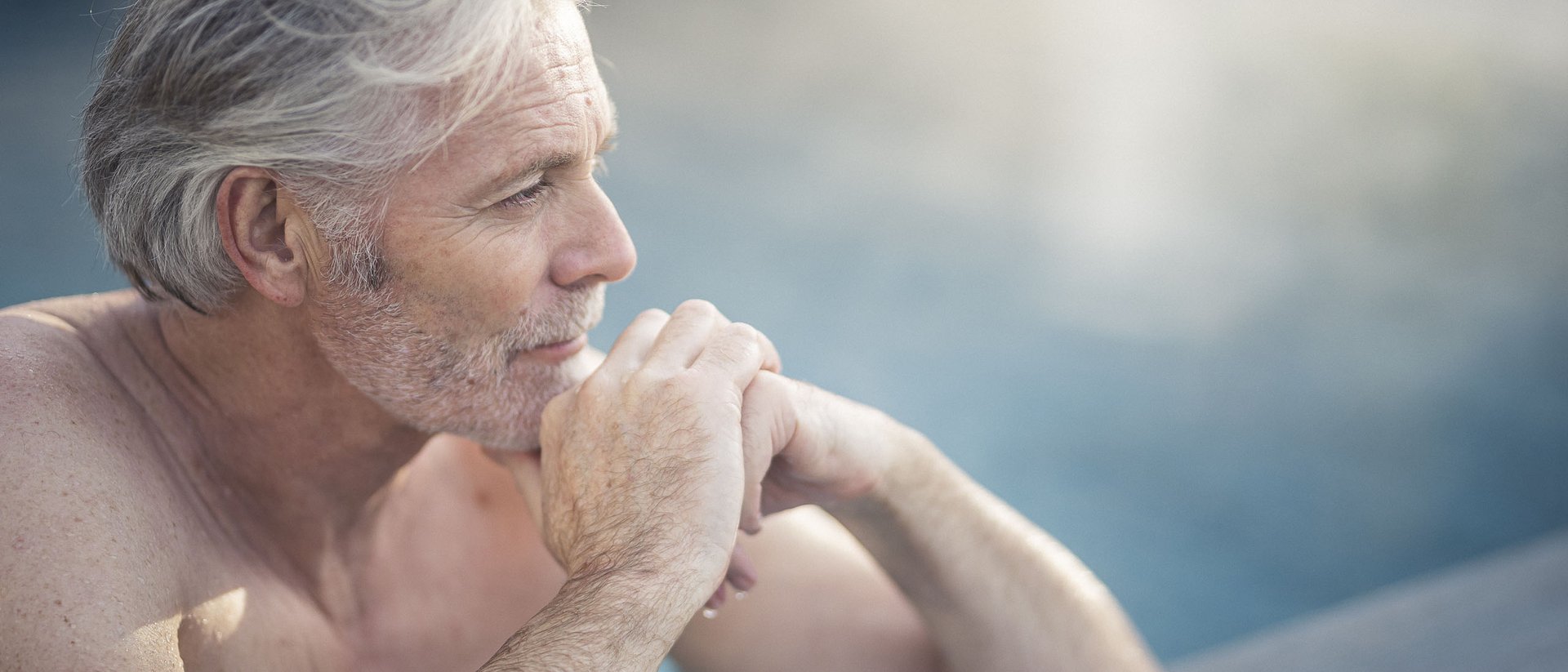 Uomo anziano rilassato in piscina con espressione pensierosa