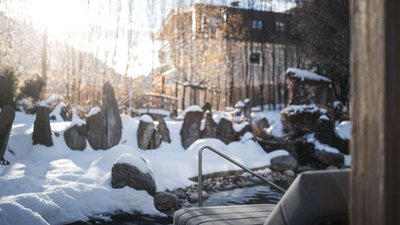 Giardino invernale con pietre innevate e struttura d'acqua al sole