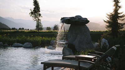 Sdraio comode accanto a una cascata in giardino al tramonto