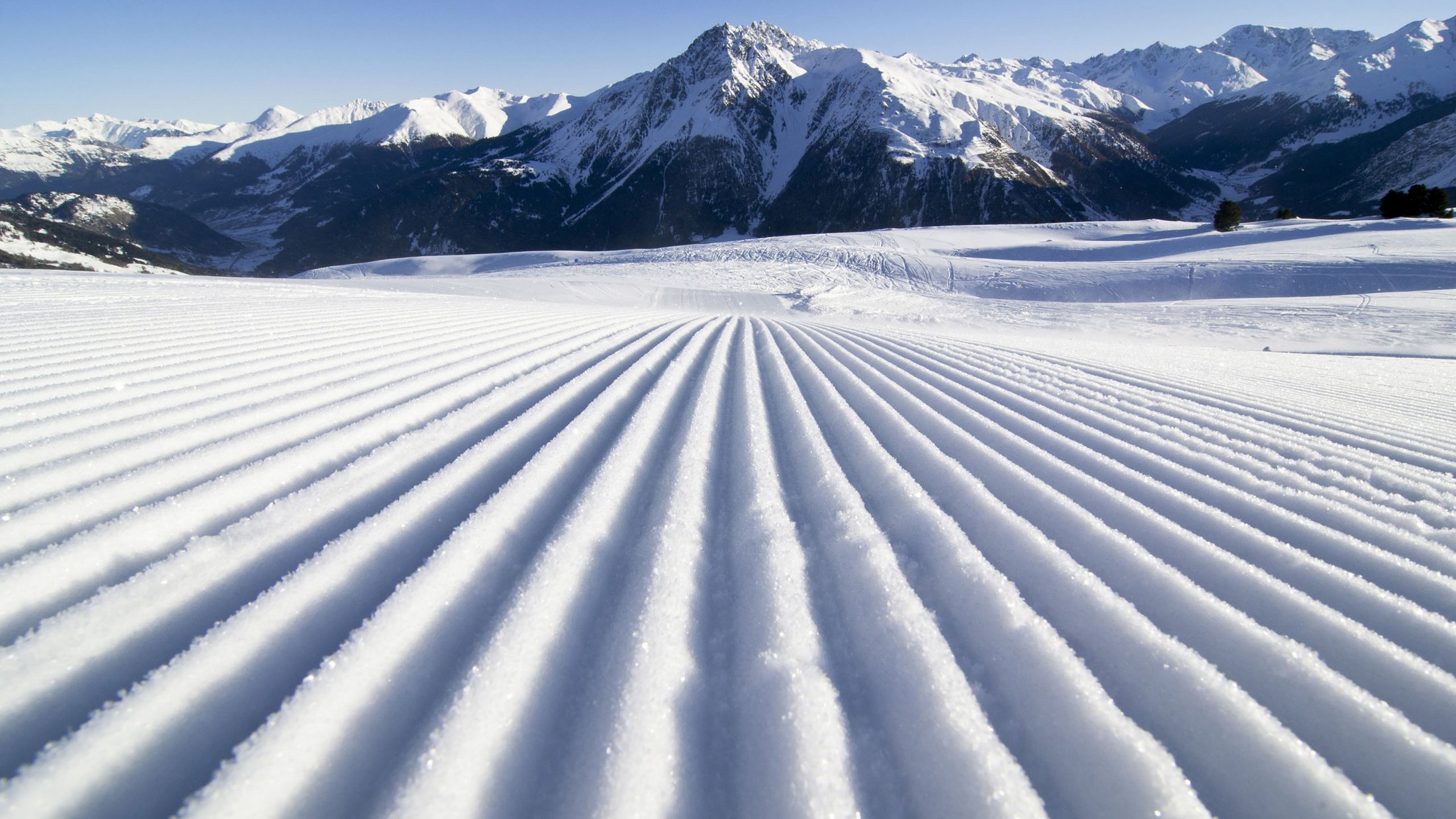 Pista da sci battuta con neve fresca davanti a montagne innevate