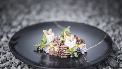 Dessert raffinato con mousse bianca, cioccolato e bacche su piatto nero