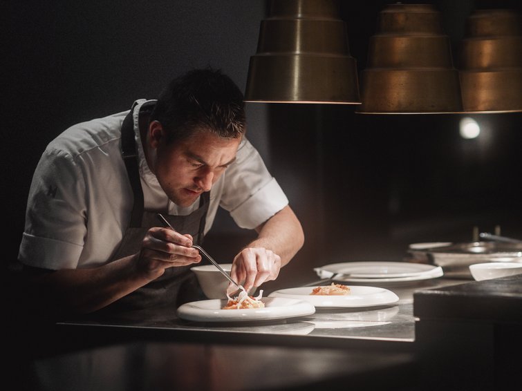 Esclusivi servizi Premium nel nostro hotel con infinity pool Cuoco che sistema il cibo nei piatti in una cucina professionale con luce soffusa