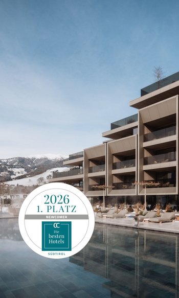 Die Heimat des Strahlens: Ihr Wellnesshotel in Südtirol Modernes Hotel mit Außenpool vor verschneiten Bergen und Auszeichnung „1. Platz 2026“