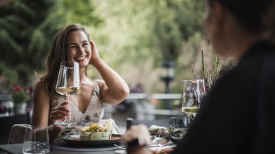 Frau beim Essen mit Weinglas in der Hand bei draußen Restaurant