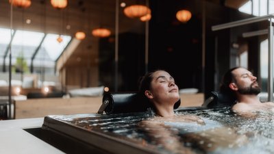 L’esclusività in foto: il nostro chalet in Alto Adige di lusso Uomo e donna rilassati in una vasca idromassaggio moderna in un ambiente interno