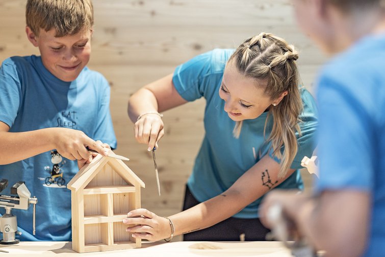 Donna e ragazzo costruiscono insieme una casetta di legno