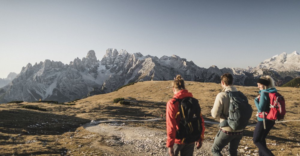 Programma di attività Tre escursionisti su un sentiero di montagna con vista sulle Alpi innevate