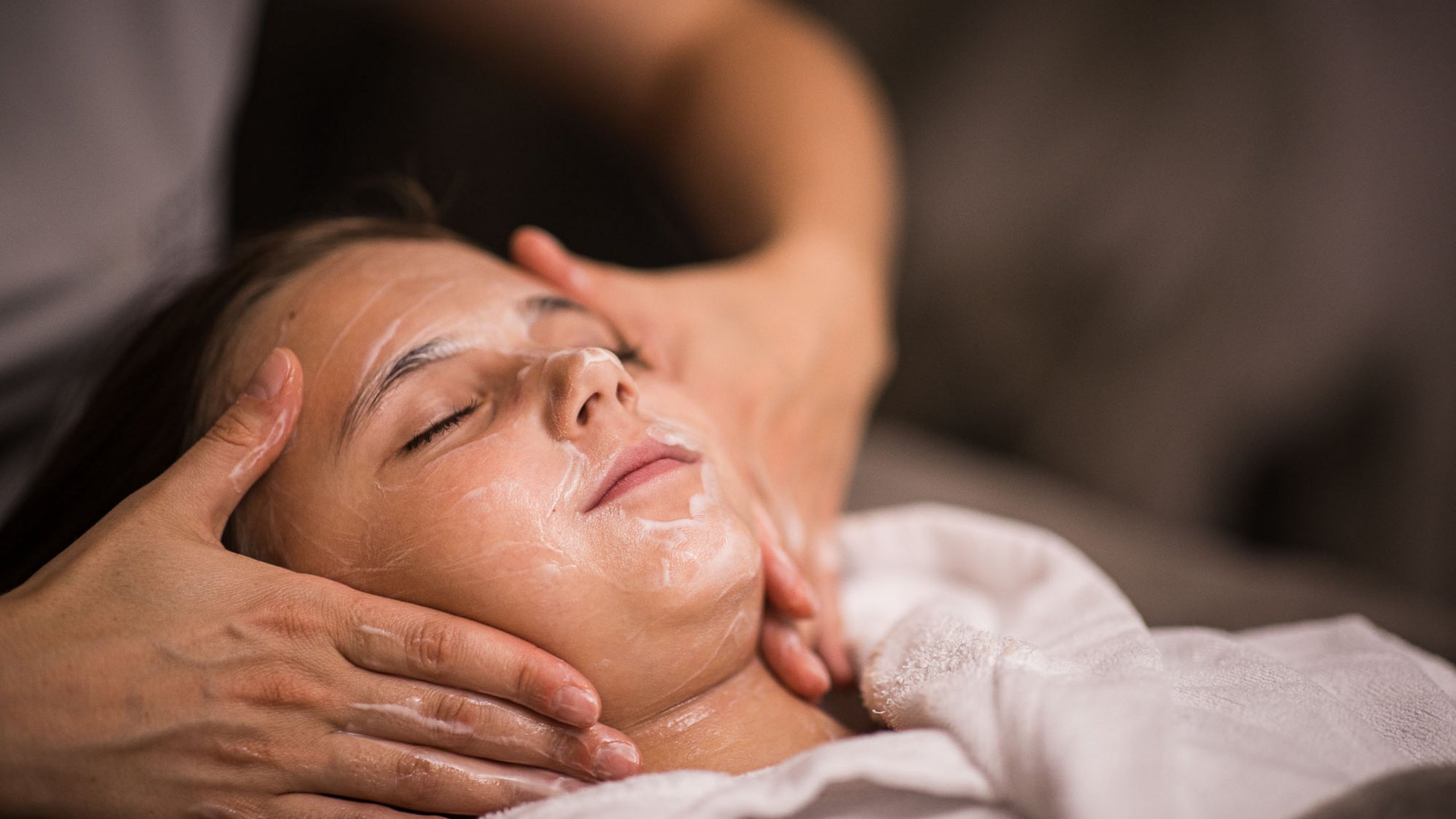 Frau erhält entspannende Gesichtsbehandlung mit Creme im Spa