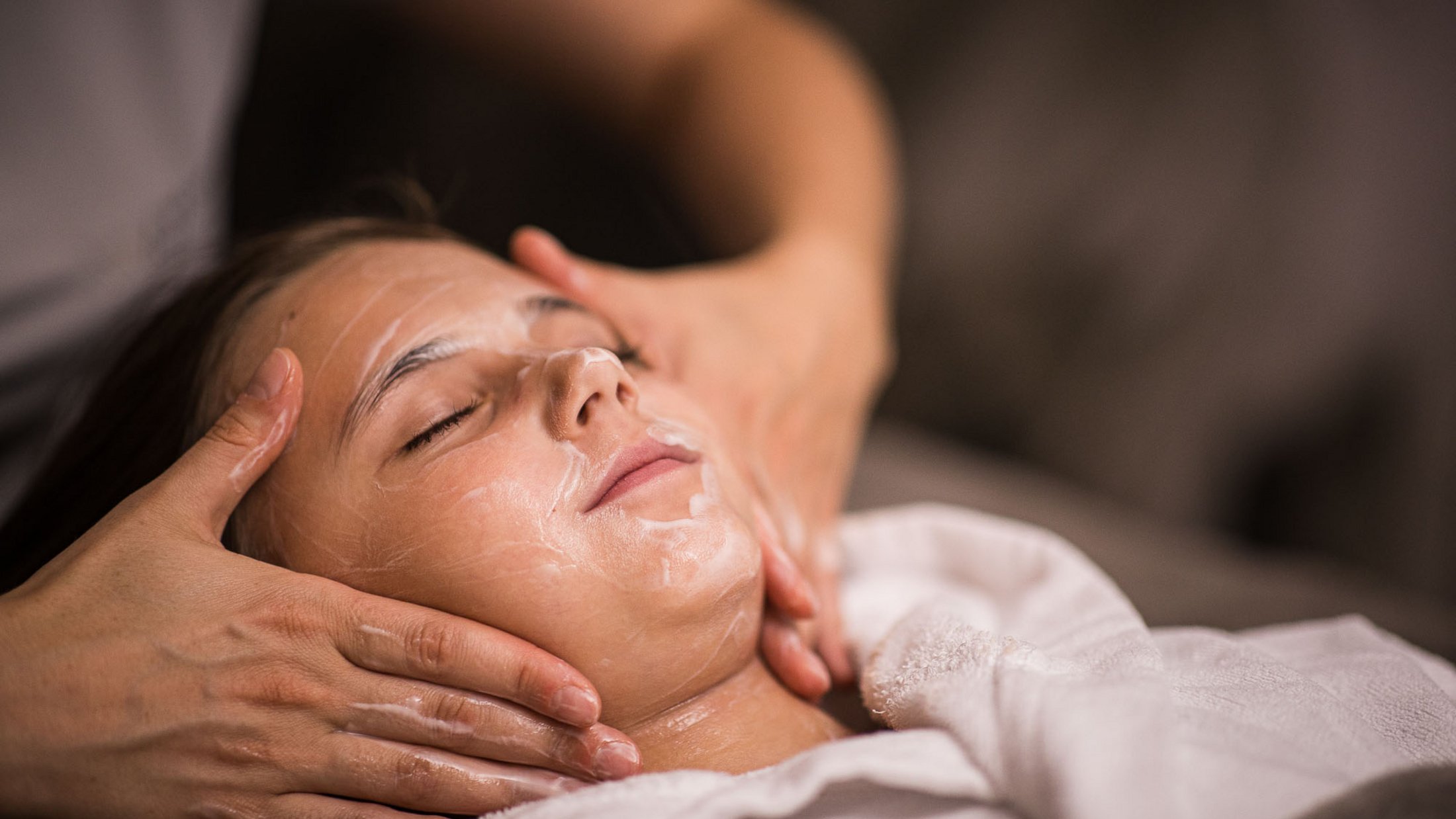 Frau erhält entspannende Gesichtsbehandlung mit Creme im Spa