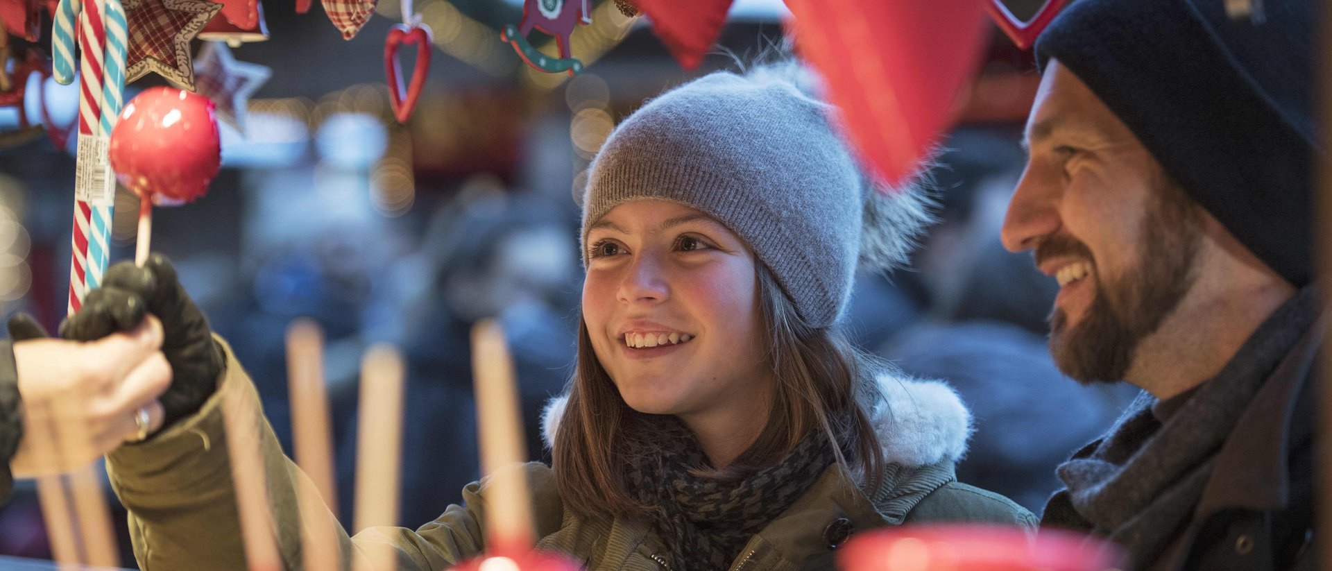 Mädchen kauft Zuckerwatte auf Weihnachtsmarkt mit Vater im Winter