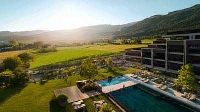 Sunrise over green fields and a hotel with pool in the mountains