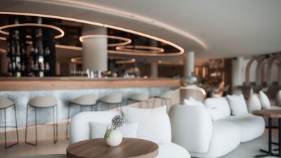 Photos from your hotel in Pfalzen in Val Pusteria/Pustertal Modern lounge area with white sofa and bar stools under indirect lighting