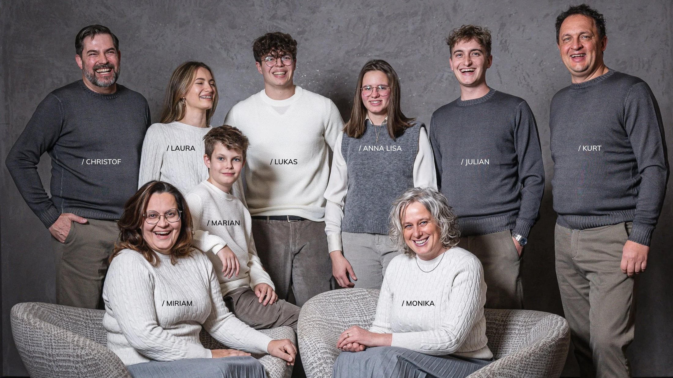 Nine people in gray and white sweaters against a gray background