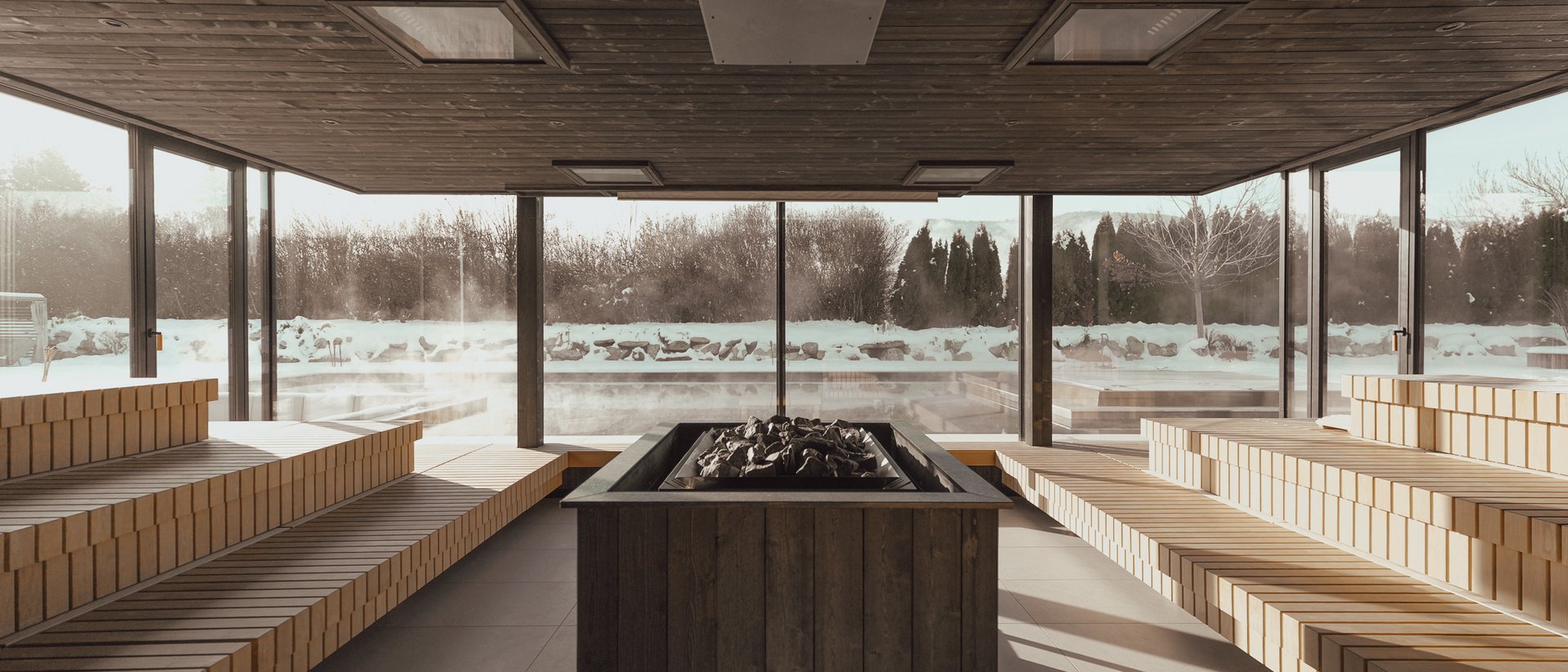 The multi-faceted Sonnenspa at our spa hotel in South Tyrol Indoor sauna with wooden benches and view of snowy landscape