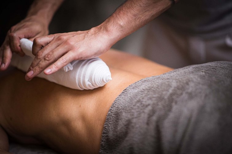 Mann erhält Rückenmassage mit warmem, feuchtem Tuch