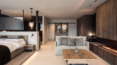 Camera da letto moderna con divano grigio, tavolo in legno e camino.