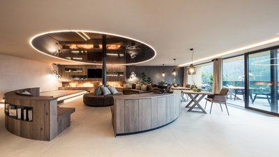 Soggiorno moderno con mobili rotondi in legno e grandi finestre con vista sulle montagne