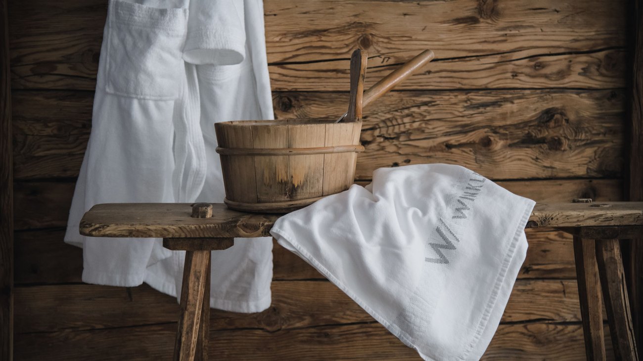 Panca da sauna con secchio di legno, mestolo e asciugamani bianchi