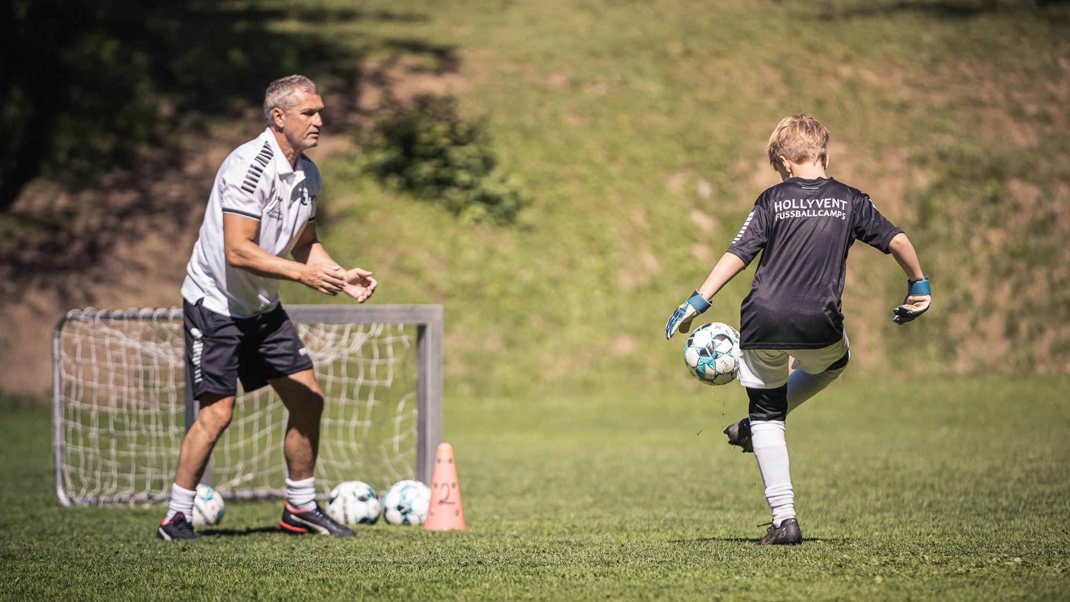 Allenatore osserva ragazzo durante allenamento di calcio sul campo verde