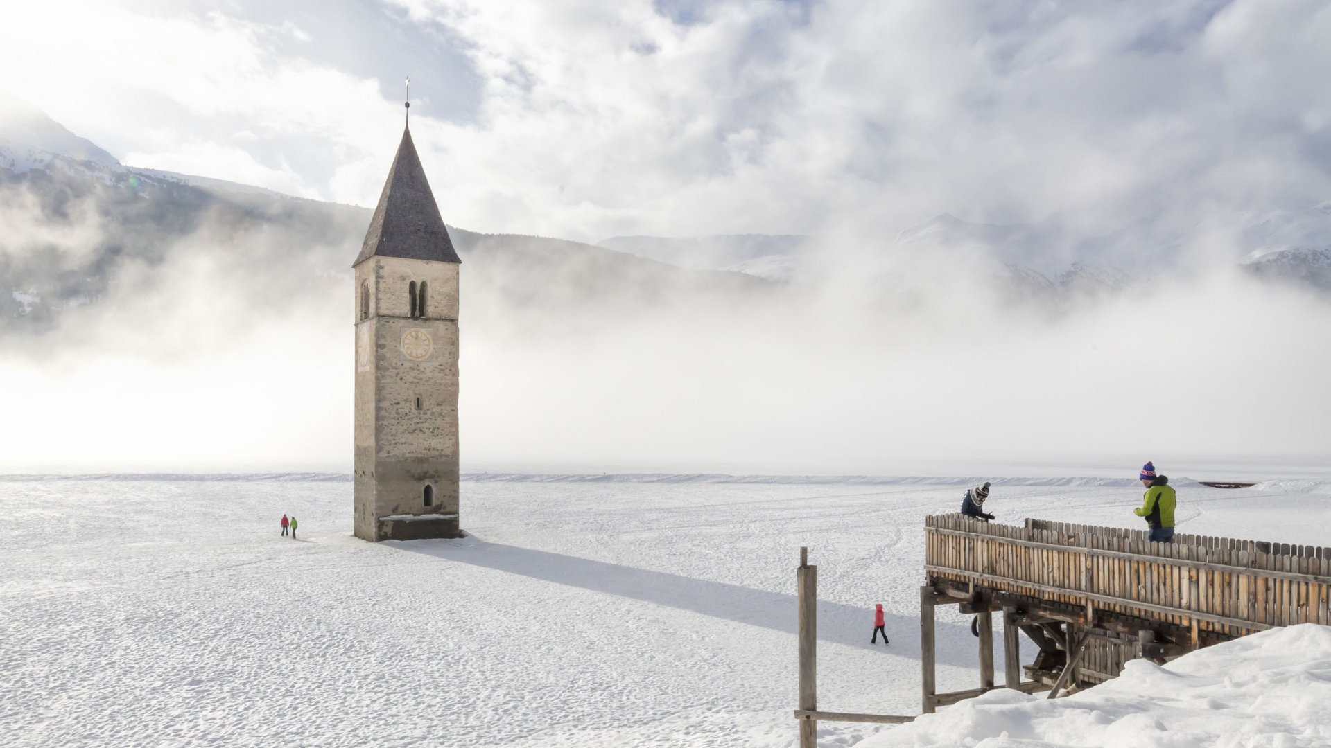 Avventure straordinarie nel nostro sporthotel in Alto Adige Campanile sommerso emerge da lago ghiacciato e innevato con nebbia