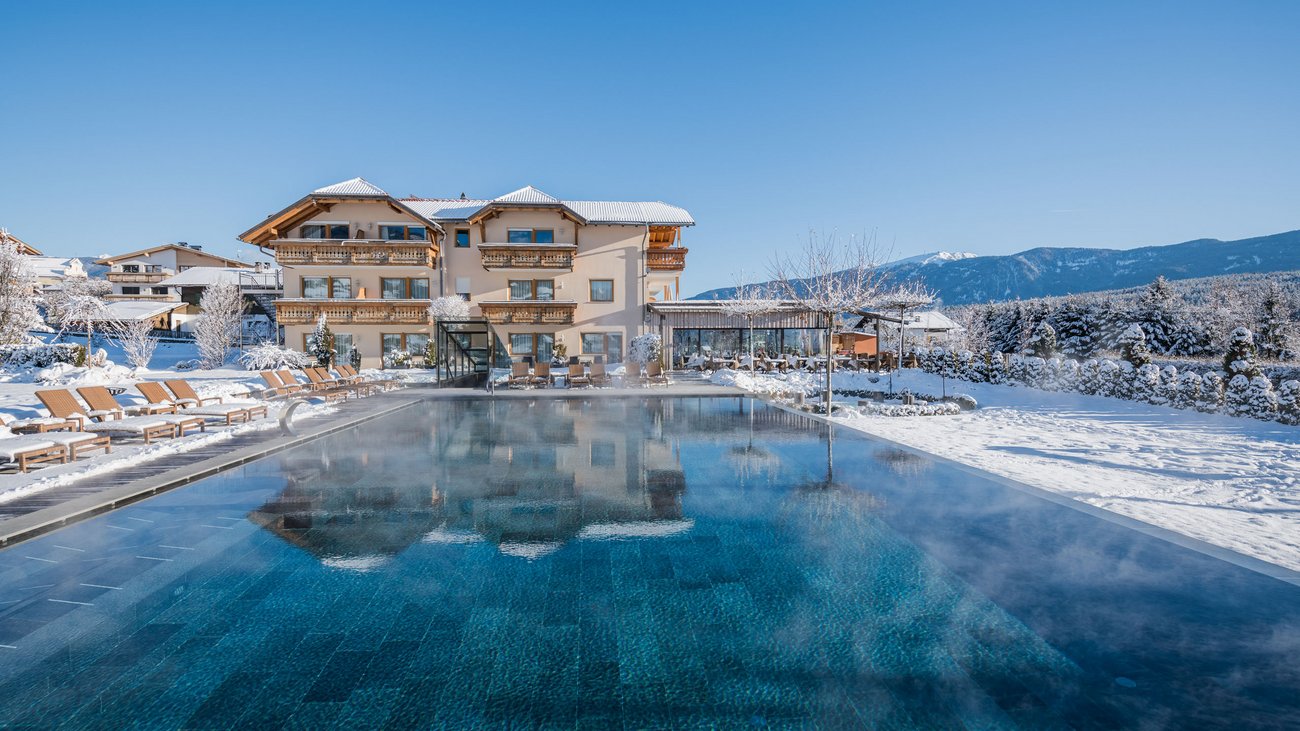 Hotel with heated outdoor pool and snow-covered garden in winter