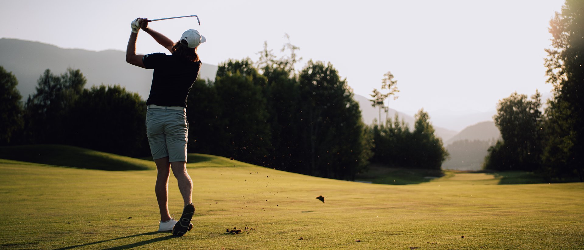 Platzreife in Südtirol erlangen: unser Premium-Golf-Service Golfspielerin beim Abschlag auf einem sonnigen Golfplatz vor Bergkulisse