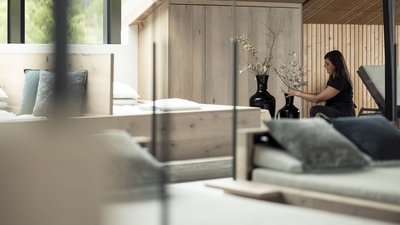 L’esclusività in foto: il nostro chalet in Alto Adige di lusso Donna che sistema vasi neri grandi con fiori secchi in una stanza moderna