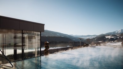 Photos from your hotel in Pfalzen in Val Pusteria/Pustertal Steaming outdoor pool with mountain view on a clear winter day