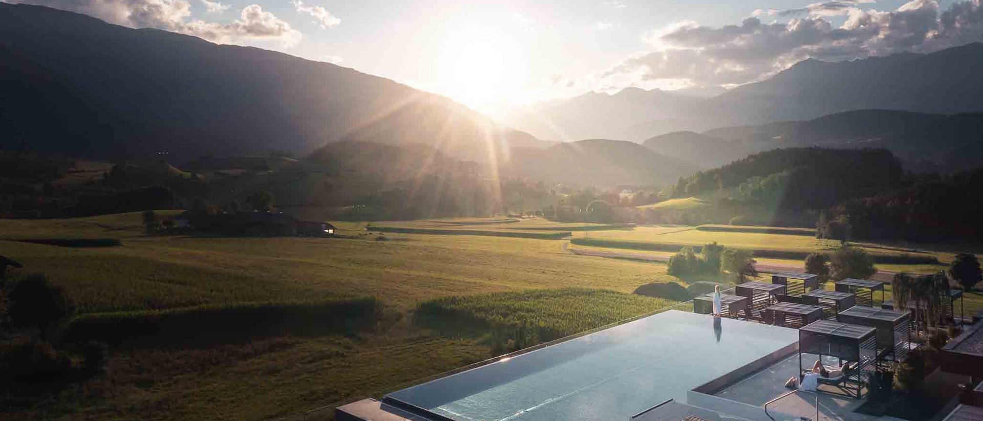 Tramonto su una valle montana con campi e piscina a sfioro