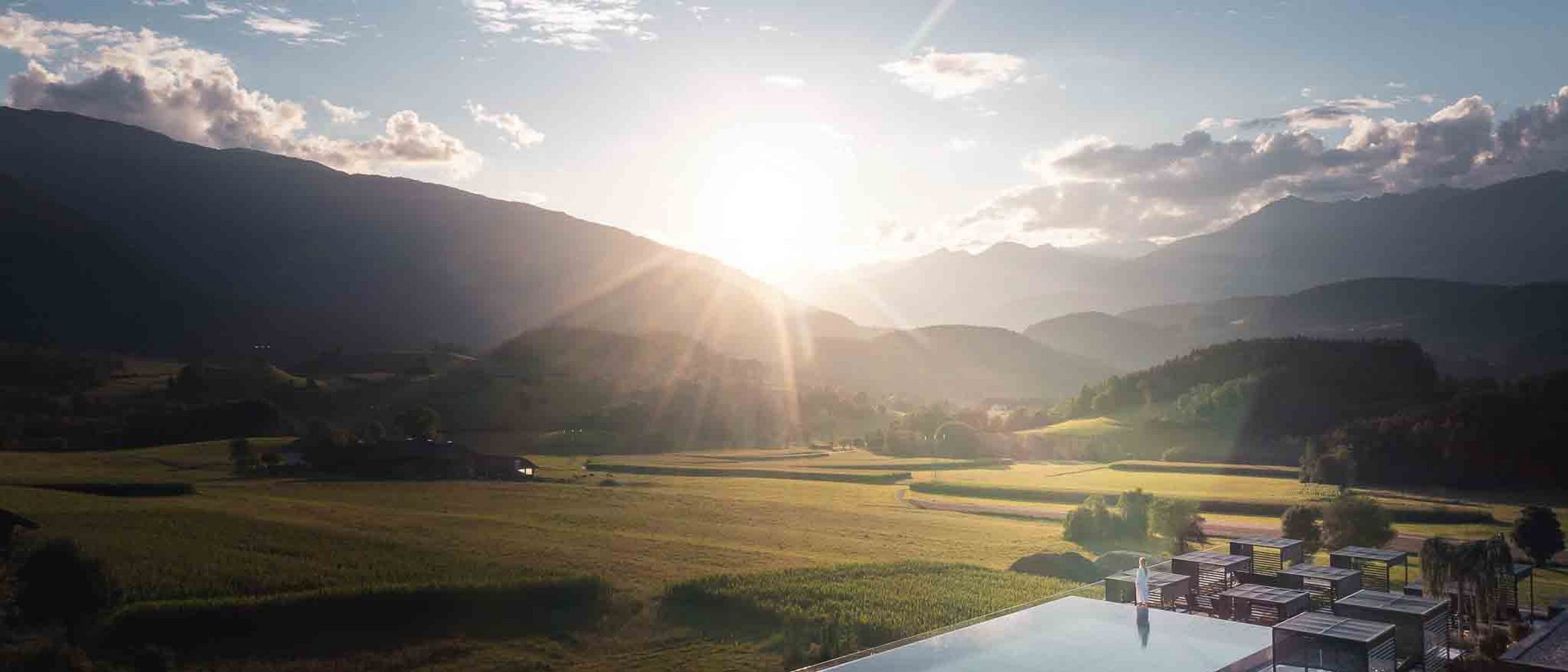 Winklerhotels | Detox und Immunstärkung im Herbst Sonnenuntergang über Bergtal mit Feldern und Infinity-Pool