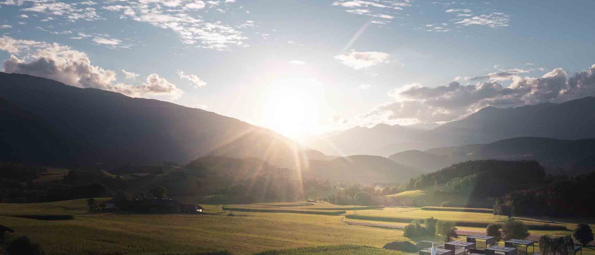 Winklerhotels | Detox e rimedi per rafforzare il sistema immunitario in autunno Tramonto su una valle montana con campi e piscina a sfioro