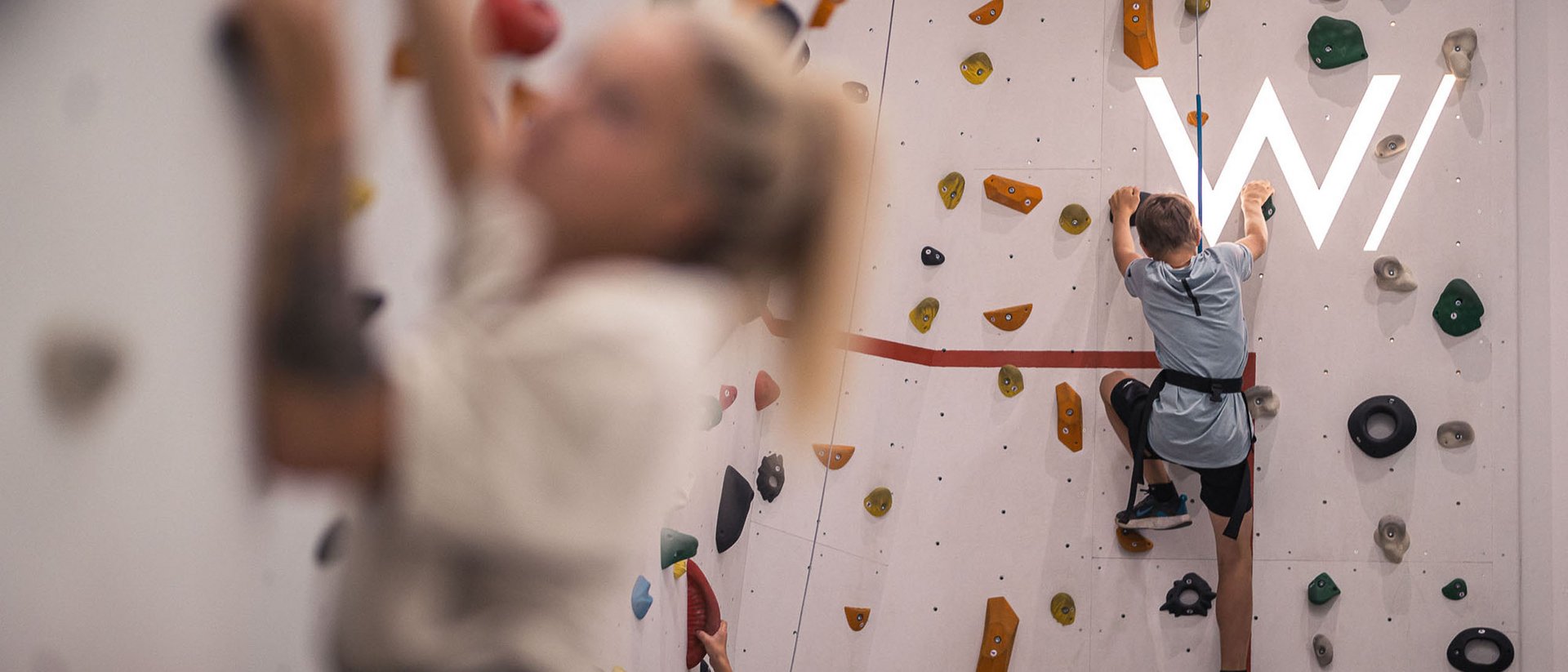 Bambini che scalano una parete da arrampicata in palestra