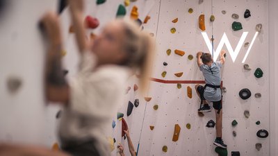 Bambini che scalano una parete da arrampicata in palestra