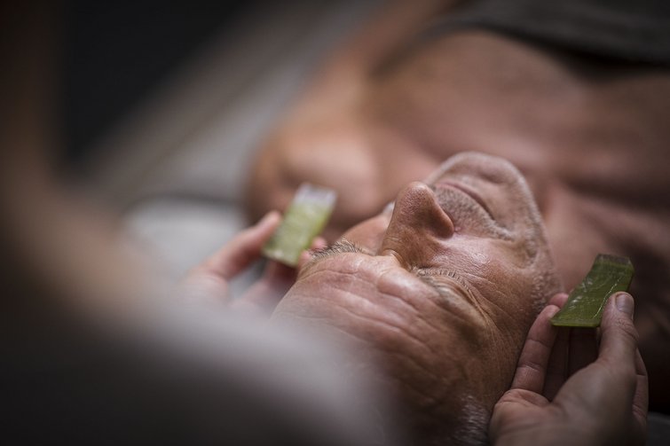 Uomo riceve massaggio agli occhi con pietre verdi in spa